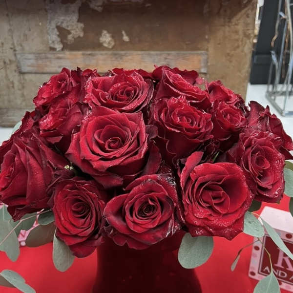 Bouquet of red roses in a dark vase with eucalyptus accents