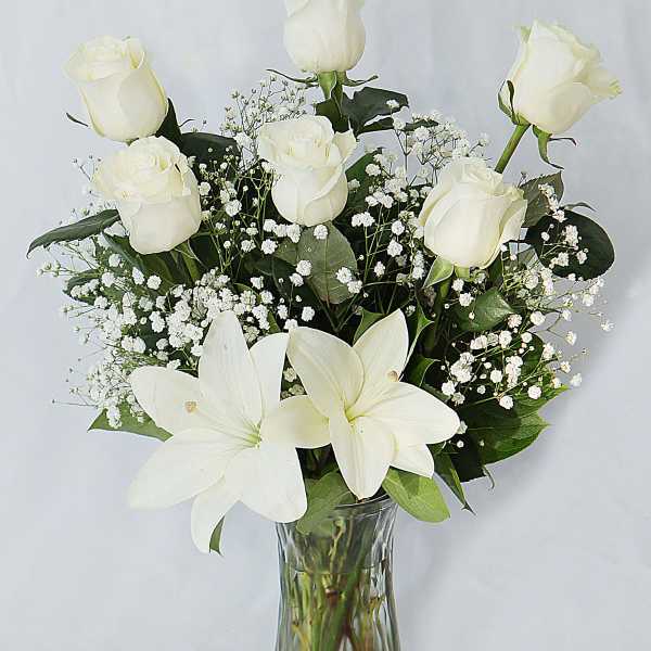 White roses and lilies arranged in a clear glass vase