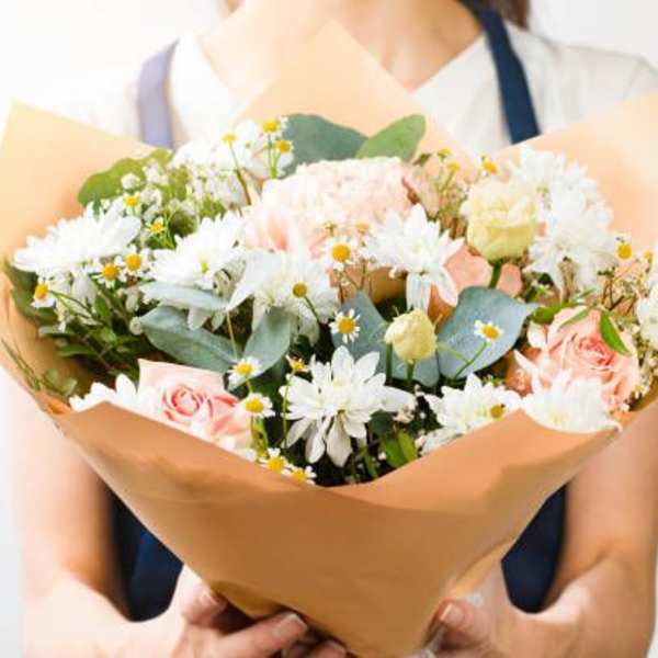Bouquet of pink roses and white daisies wrapped in tan paper