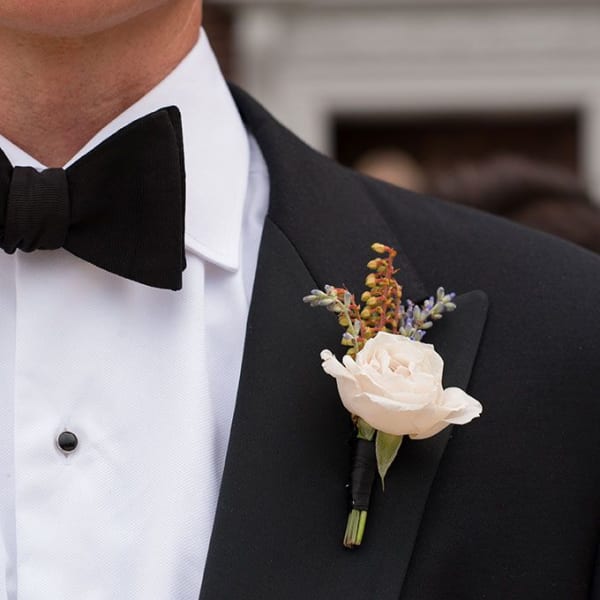 White rose boutonniere on a black tuxedo lapel