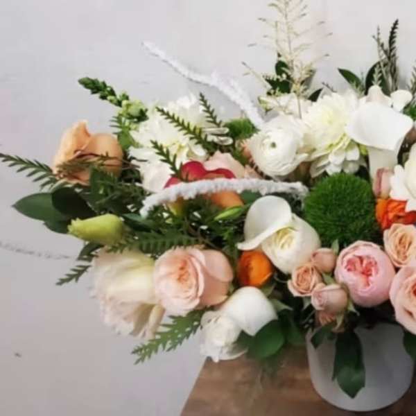 Low floral arrangement with white and blush blooms in a white vase