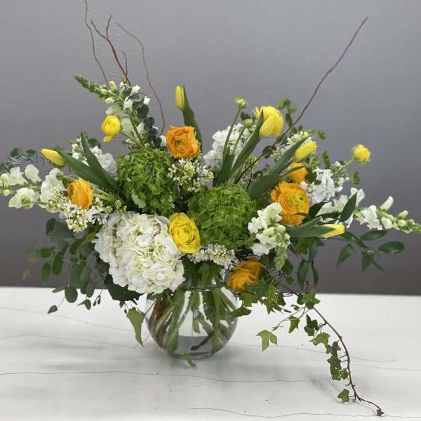 Yellow and white mixed flower arrangement in a clear glass vase