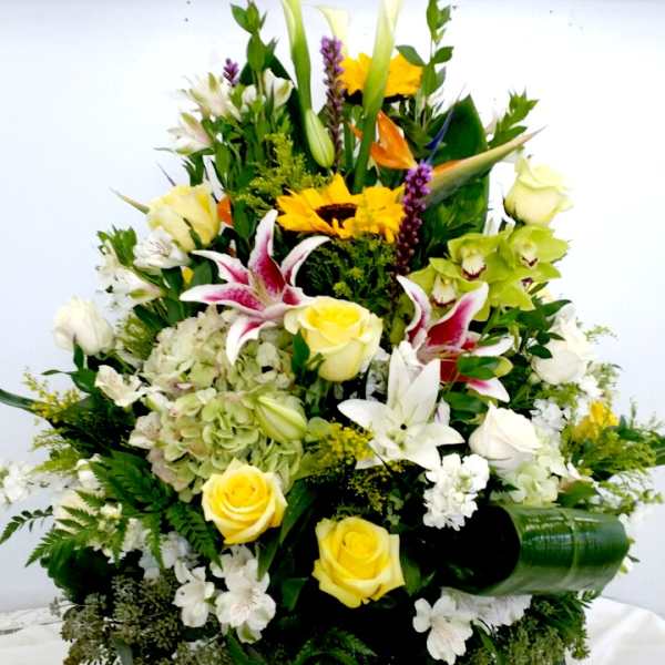 Large mixed floral arrangement with yellow roses and white lilies in a vase