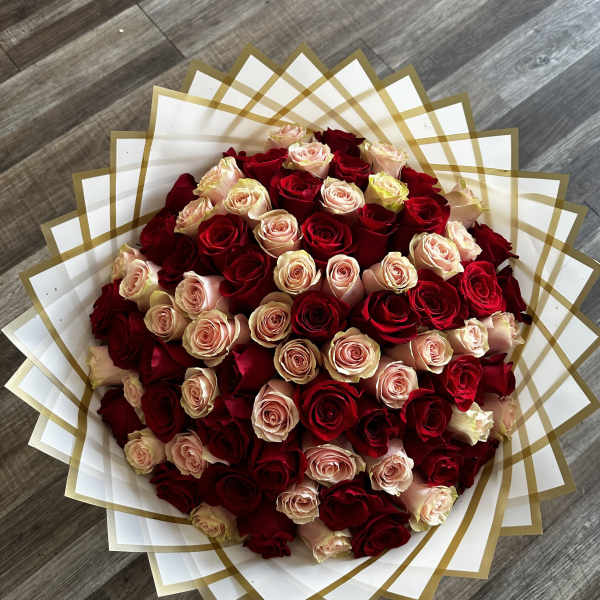 Large bouquet of red and blush roses wrapped in white and gold paper