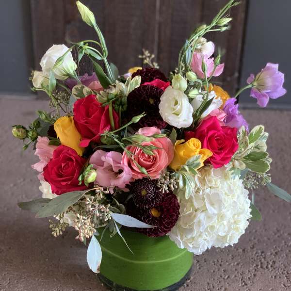 Mixed bouquet of roses, lisianthus, and hydrangea in a green vase