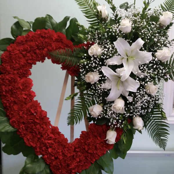Heart-shaped red floral wreath beside a white lily and rose spray