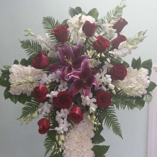 Standing floral cross with red roses, white flowers, and purple lilies