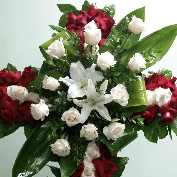 Cross-shaped floral arrangement of red and white roses with lilies