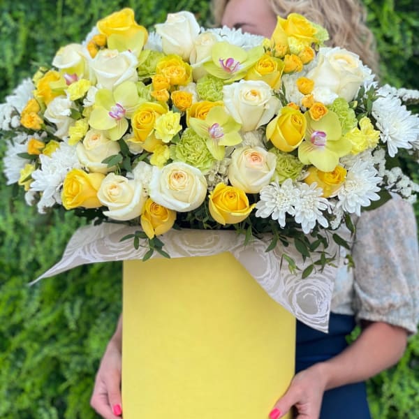 Yellow and white bouquet with roses, orchids, and daisies in a yellow box