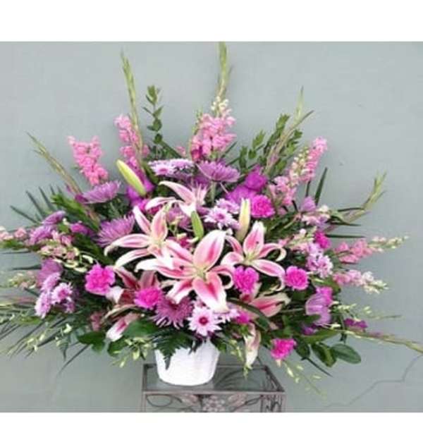 Pink lilies and mixed purple flowers in a white vase