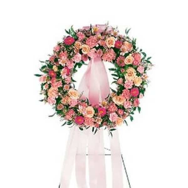Pink and peach floral wreath on a pink stand with ribbon