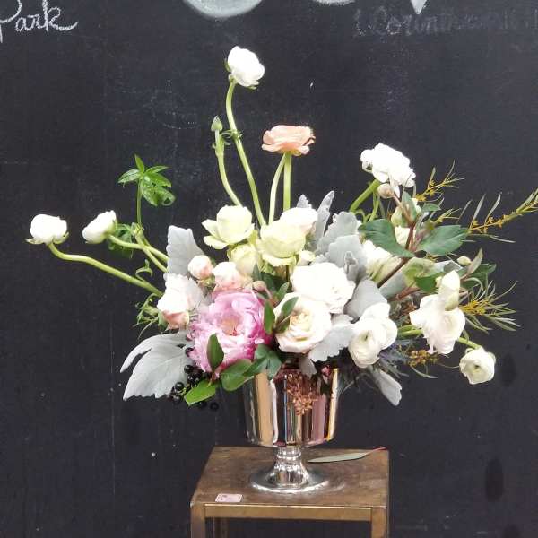 Pastel floral arrangement in a silver pedestal vase