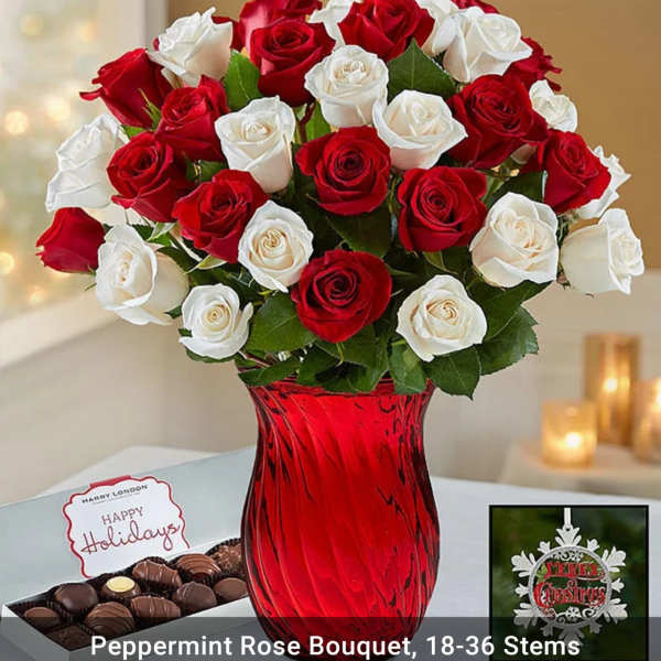 Red and white roses in a red glass vase with chocolates and a holiday card