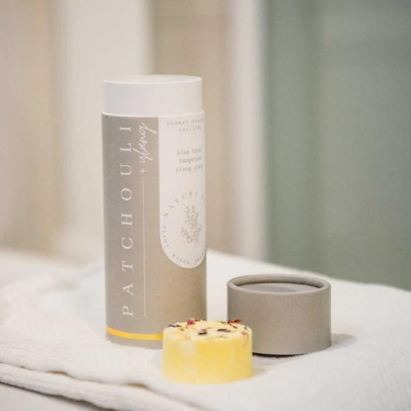 Patchouli shower steamers in a tube with a small yellow bar and lid