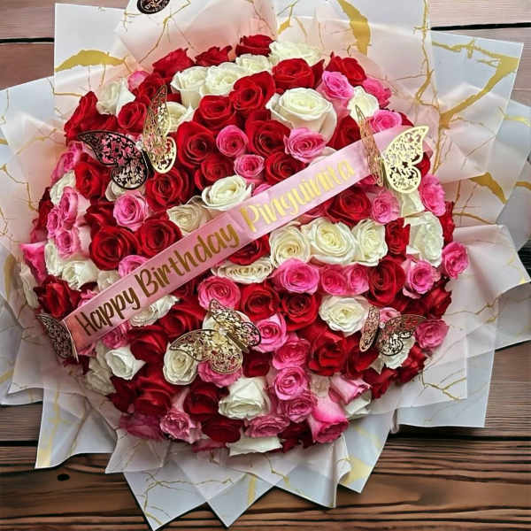 Round bouquet of red, pink, and white roses with a birthday ribbon and butterfly picks