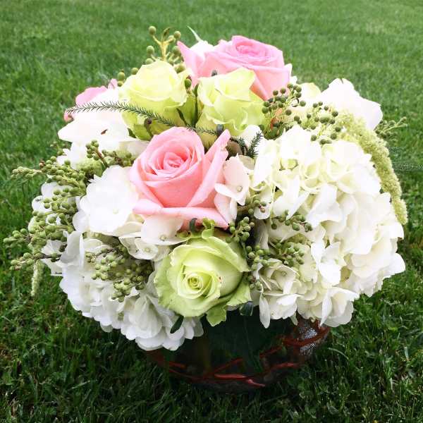 Pink and green roses with white hydrangeas in a basket