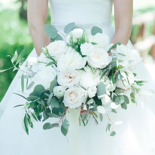 Bride holding a white bouquet with greenery