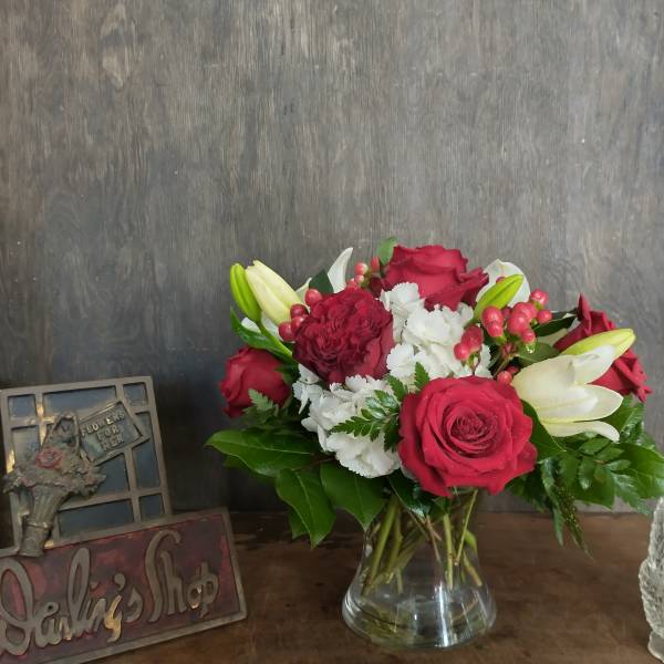Bouquet of red roses, white lilies, and white carnations in a glass vase