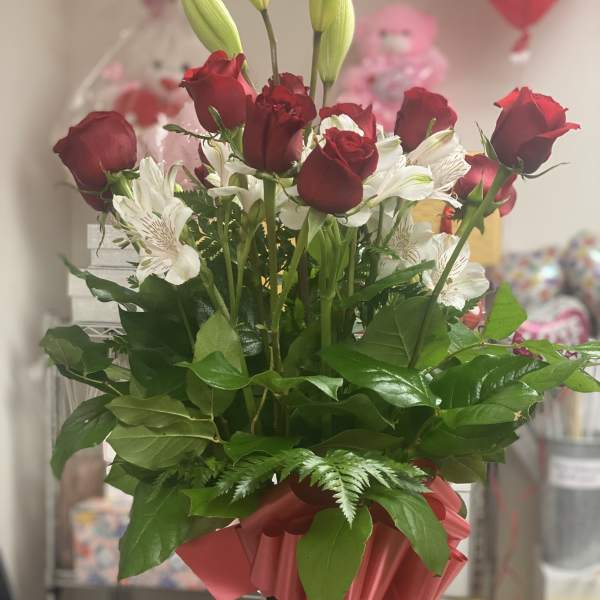 Red roses and white alstroemeria in a black vase with a pink ribbon