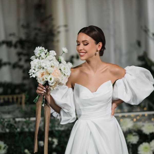 Bride holding a white wedding bouquet with long ribbon streamers