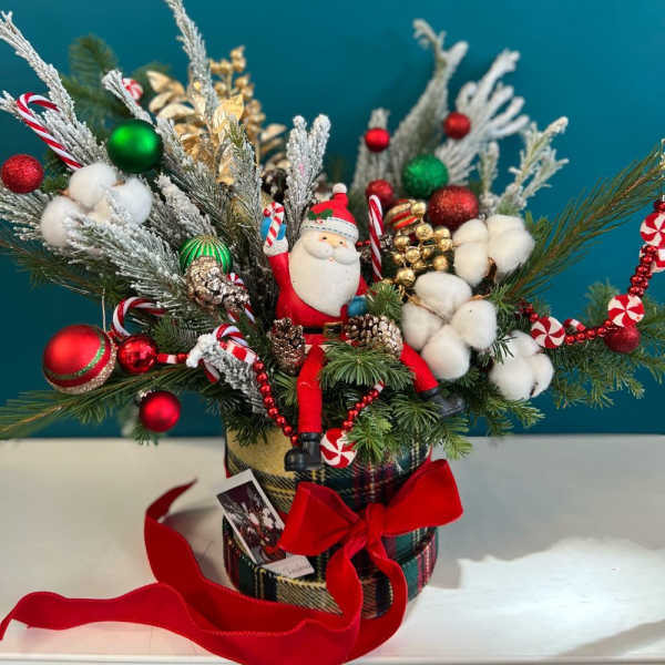 Christmas arrangement with Santa figurine, ornaments, and cotton stems in a plaid container