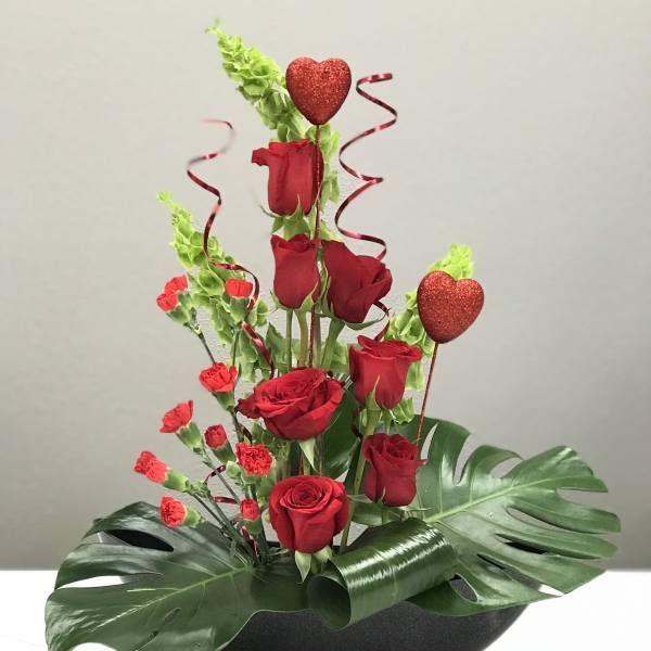 Red roses and carnations in a black bowl with heart picks