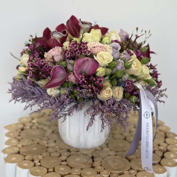 Bouquet of pink, cream, and purple flowers in a white vase