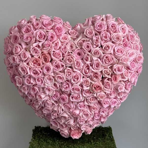 Heart-shaped arrangement of pink roses on a moss-covered base