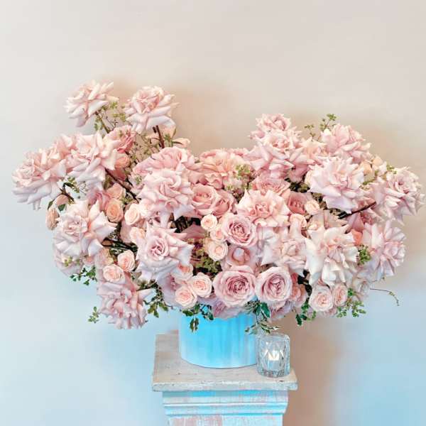Large pink rose arrangement in a blue container on a pedestal