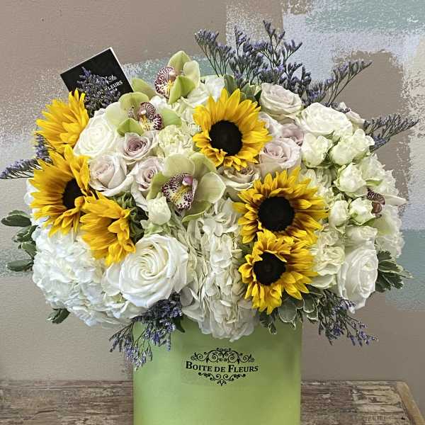Mixed bouquet with sunflowers, white roses, and orchids in a green box