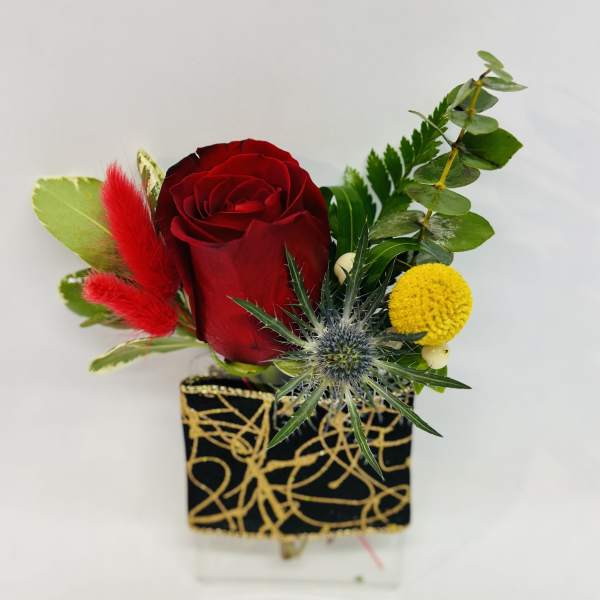 Red rose arrangement in a black and gold square vase