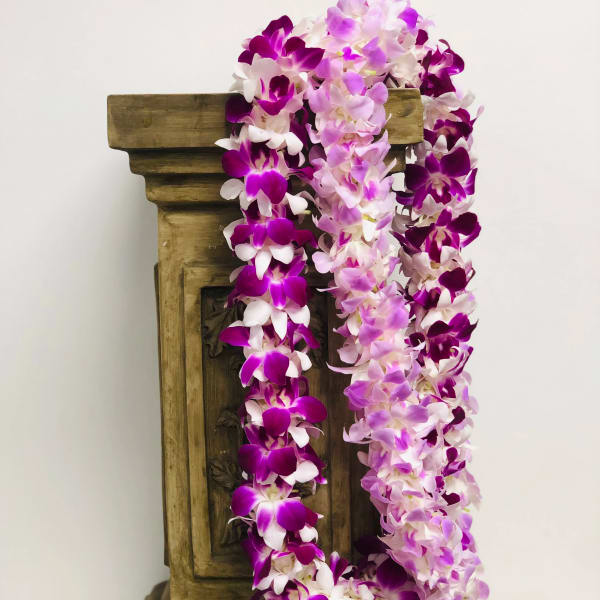 Purple and pink orchid garlands draped over a wooden pedestal
