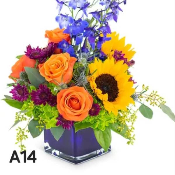 Colorful bouquet with roses, sunflower, and blue flowers in a square vase