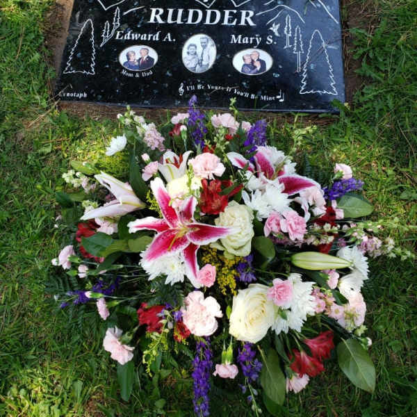 Floral grave arrangement below a memorial headstone
