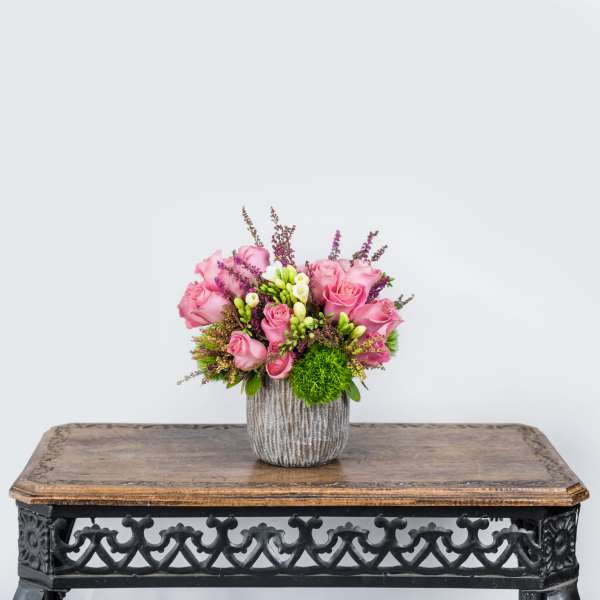 Pink roses arranged in a textured vase on a table