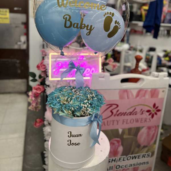 Blue balloon bouquet above a white hatbox of turquoise roses with "Welcome Baby" text