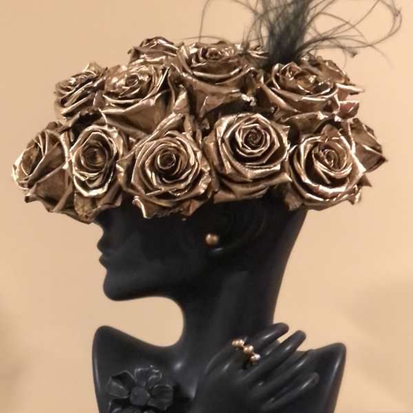 Black bust sculpture topped with metallic gold roses and feather accents