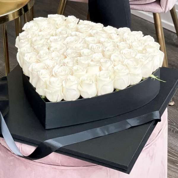 Heart-shaped box filled with white roses and black ribbon