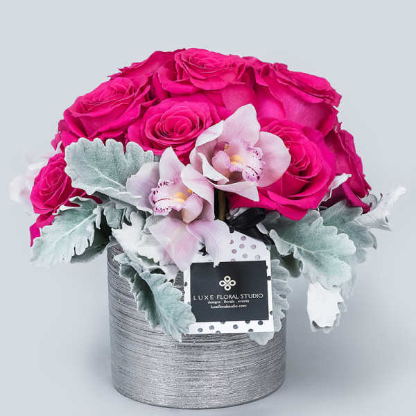Pink roses and pale orchids in a silver round box