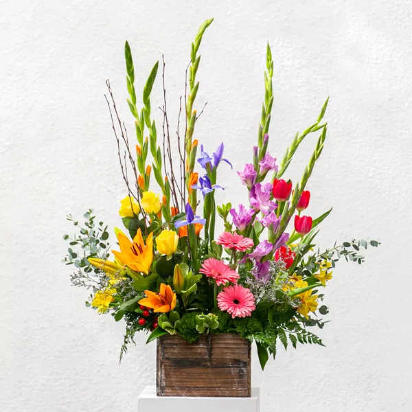 Tall mixed bouquet in a wooden box with lilies, tulips, and gerbera daisies