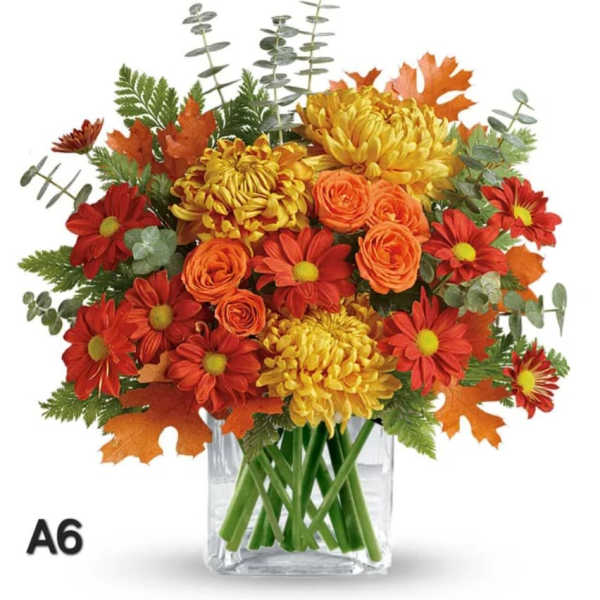 Autumn bouquet of red, orange, and yellow flowers in a clear glass vase