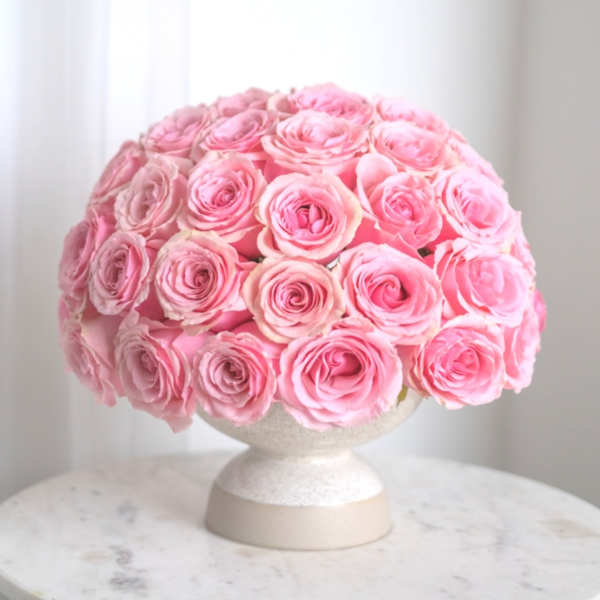 Round bouquet of pink roses in a white pedestal vase