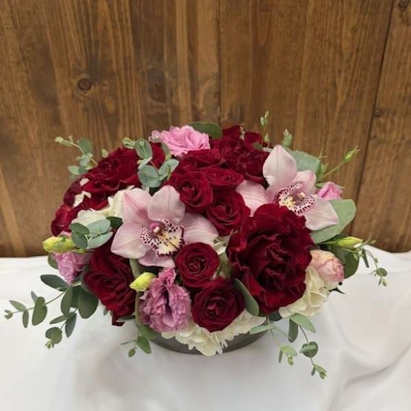 Bouquet of red roses and pink orchids in a low vase