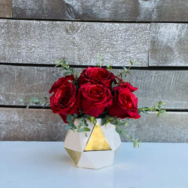 Red roses in a geometric white and gold vase