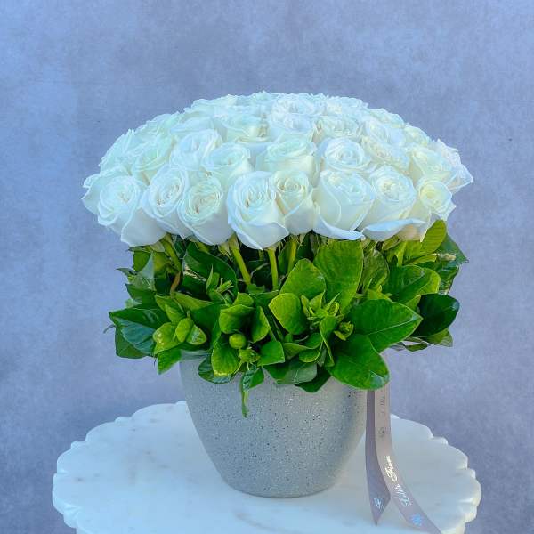 Round bouquet of white roses in a speckled gray vase