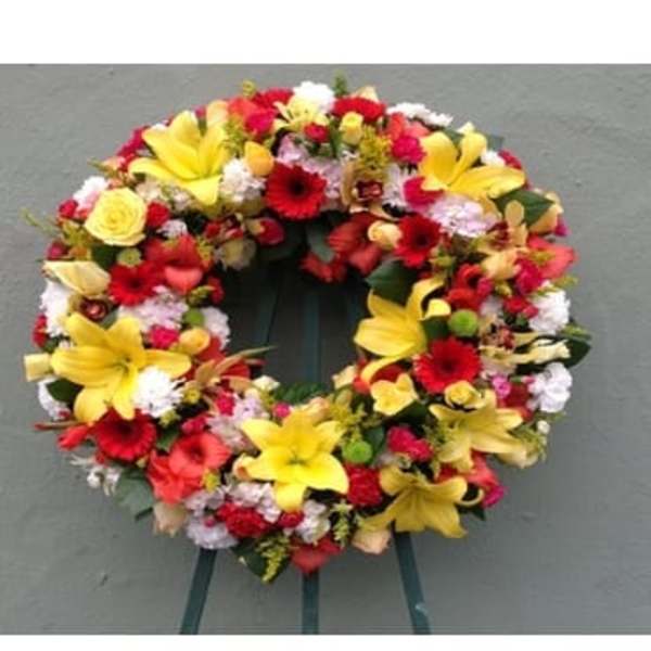 Colorful floral wreath with yellow lilies and red blooms