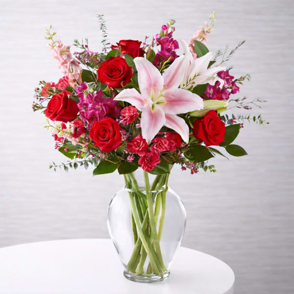 Bouquet of red roses and pink lilies in a clear glass vase