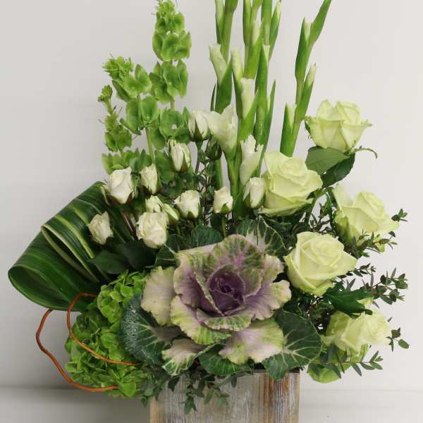 Green and white floral arrangement in a wooden box with roses and tall stems