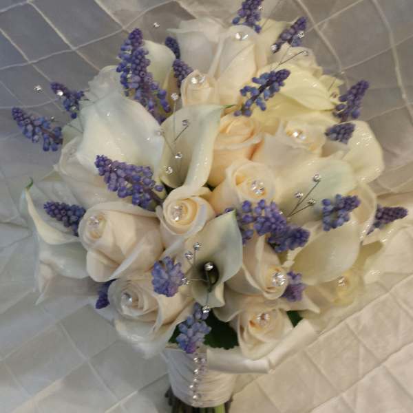 Cream roses and purple filler flowers in a bridal bouquet