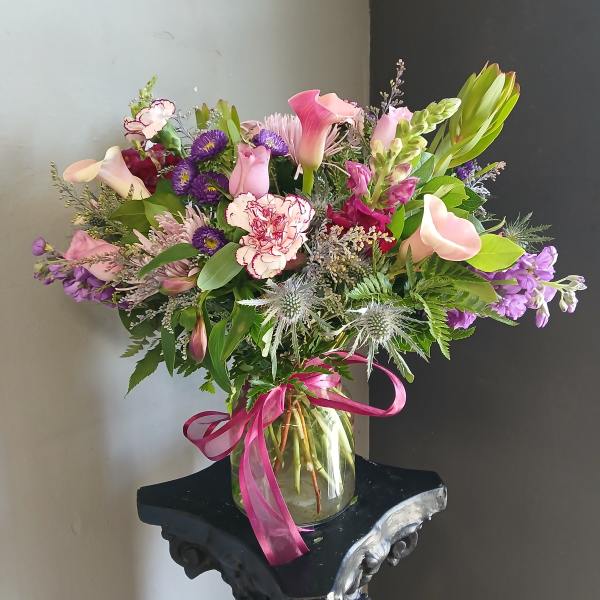 Pink and purple mixed bouquet in a glass vase with a ribbon